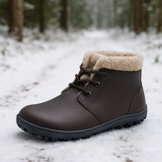 En närbild på en barfotasko med tjockt ullfoder, stående på snöig skogsstig. Alt: barfotaskor med ullfoder vinter – varm och greppsäker på snö.